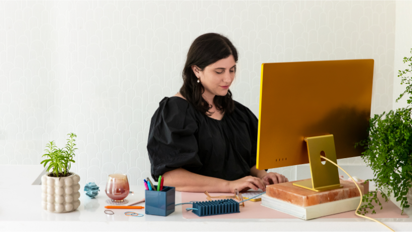 A woman typing at her computer as she builds a professional-looking website in Mailchimp.