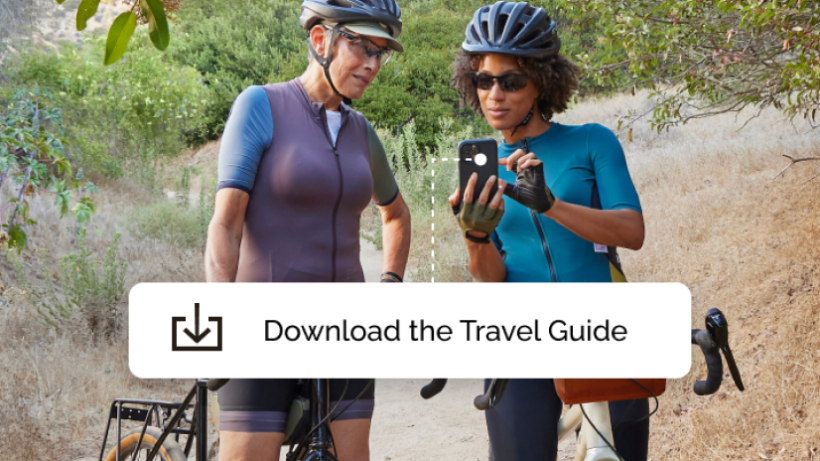 Two women on a cycling tour, pausing to download a Travel Guide app offered by a Mailchimp campaign.