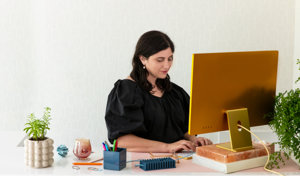 A woman typing at her computer as she runs her e-commerce company from her desk.
